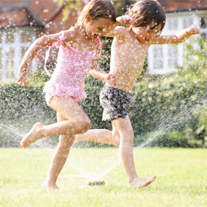 Summertime fun on a budget kids running through sprinkler 